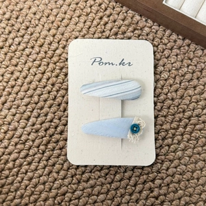 Close-up of light blue floral fabric hair clips with lace trim on a card display