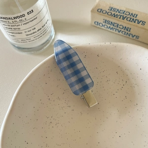 Detail showing blue and white checkered pattern hair clip on a decorative ceramic tray