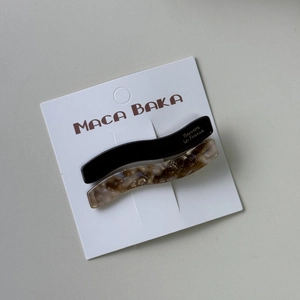 Set of two wavy acetate hair clips in solid black and tortoise shell pattern on card