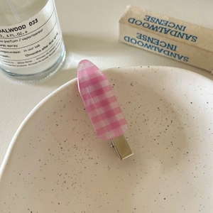 Detailed view of pink checkered hair clip on a ceramic tray with a soft aesthetic