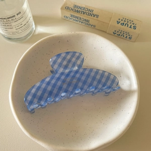Blue and white checkered hair claw clip in a ceramic bowl with a cozy lifestyle background