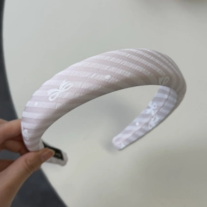 Détail d'un bandeau en tissu rayé rose et blanc avec motif de papillons imprimés