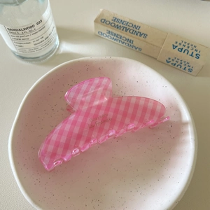 Detailed view of a pink checkered hair claw clip displayed on a stylish ceramic plate