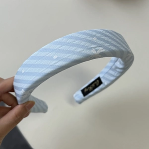 Détail du serre-tête en tissu rayé bleu et blanc avec étiquette de marque à l'intérieur