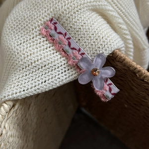 Dettaglio del fermaglio per capelli a fiori rosa con fiore viola e gemma lucente