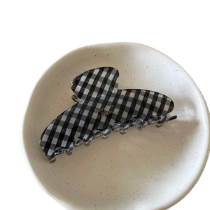 Chic black and white checkered hair claw clip with gold lettering on ceramic plate