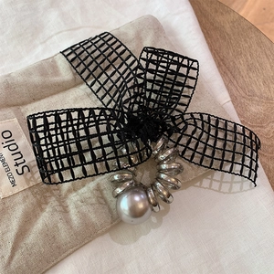 Detail of black mesh bow hair tie with silver spiral coil and large grey pearl bead
