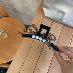 Detail einer schwarzen Haarspange mit Netzschleife und vier eleganten weißen Perlen für Frisuren