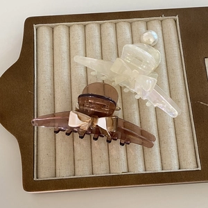 Elegant bow hair claws in cream white and coffee brown acetate with pearls on velvet tray