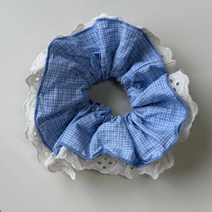 Detail of blue plaid fabric hair scrunchie with white lace trim and neat pleats