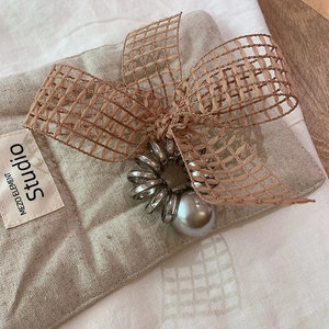 Detail of silver telephone wire hair tie with a grey pearl and brown plaid bow