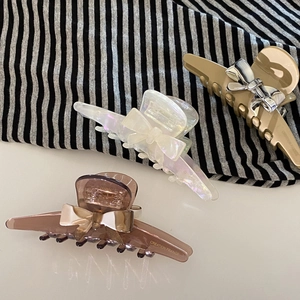 Three acetate bow hair claws in brown, pearly white, and khaki for elegant hair styling
