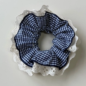 Close-up of black and white gingham scrunchie with detailed white eyelet lace trim