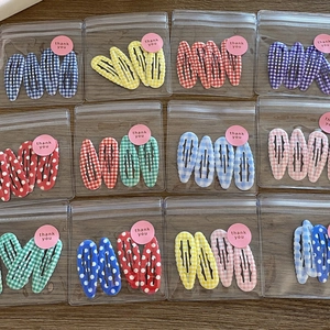 Colorful gingham and polka dot snap hair clip sets displayed on a wooden surface