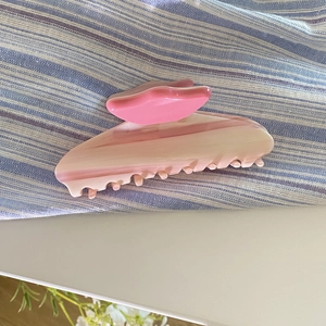 Gros plan d'une pince à cheveux en acétate dégradé rose avec texture marbrée élégante
