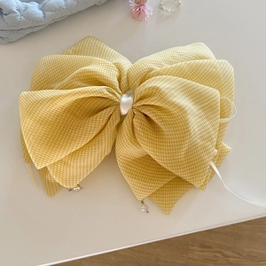 Detail of yellow gingham bow hair clip with crystal pendants and delicate tulle fabric