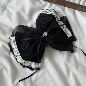 Détail de la pince à cheveux en mousseline plissée noire avec dentelle blanche