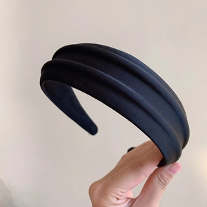 Gros plan sur un serre-tête en velours noir avec un design plissé 3D et une texture douce