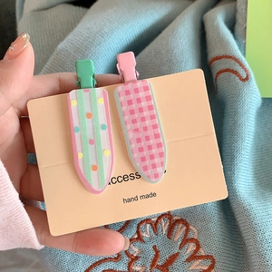 Détail de barrettes en acrylique à fleurs et carreaux sur carte de présentation bio