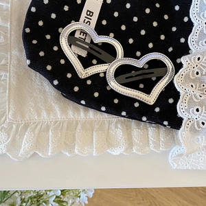 Detail view of heart-shaped silver hair clips on a decorative lace background