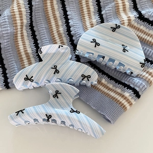 Light blue striped hair claws with black bow patterns on textured acrylic fabric