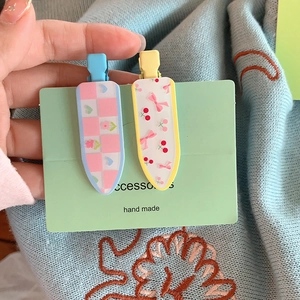 Détail de barrettes à cheveux en acrylique à fleurs et cerises avec nœuds sur carte