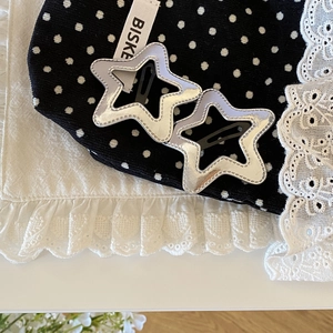 Macro detail of silver star-shaped hair clips with decorative stitching on lace background