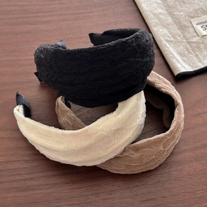 Three wide pleated chiffon headbands in black, beige, and light brown on a wooden surface