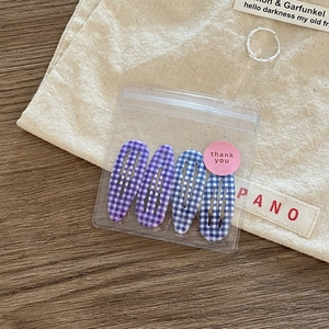 Set of four blue and purple checkered BB hair clips in gift packaging on wooden background