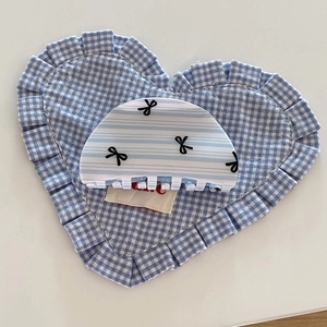 Detail of blue striped hair claw clip with bow patterns on a soft gingham cushion