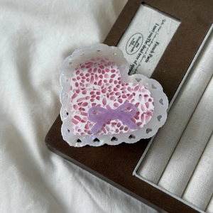 Close-up of heart-shaped acetic hair claw with lace hollow edges and pink bow detail