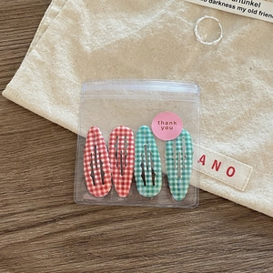 Close-up of 4-piece red and green plaid BB hair clips in gift packaging with sticker