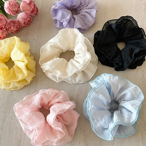 Set of 6 colorful oversized ruffled organza scrunchies in pastel tones on marble background