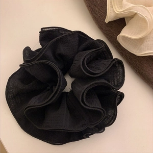 Detail of a large black pleated scrunchie showing fine fabric texture and ruffled edges