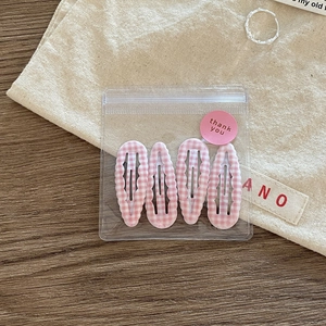 Detailed view of four pink plaid checkered hair clips in transparent gift packaging