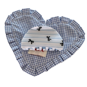 Blue and white striped hair claw clip with bow design on a soft checkered cushion