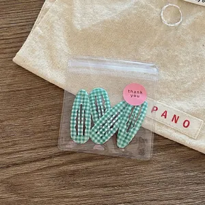 Three-piece green checkered wave hair clips in premium transparent gift packaging