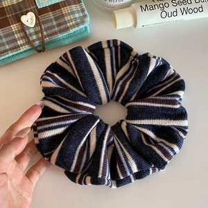 Detail of vintage striped knit scrunchie held by hand in a cozy daily lifestyle setting
