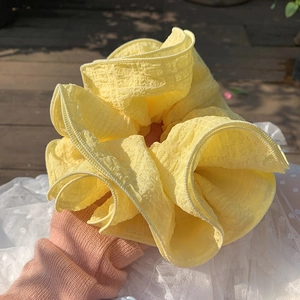 Detail shot of bright yellow oversized scrunchie showing bubbly texture in outdoor light