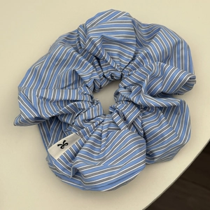 Close-up of blue and white striped scrunchie showing fabric texture and bow logo tag