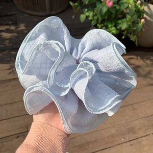 Macro detail of large light blue oversized scrunchie with seersucker textured fabric