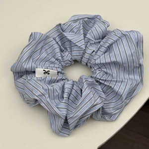Close-up of blue and white striped cotton scrunchie with detailed logo tag