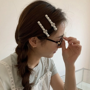 Barrettes élégantes en argent avec perles et strass portées sur le côté par un modèle