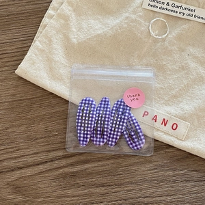Detail view of 4-piece set of purple plaid hair clips in elegant thank you packaging
