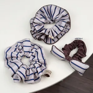 Vue détaillée de trois chouchous en tissu avec rayures bleu marine et nœud papillon