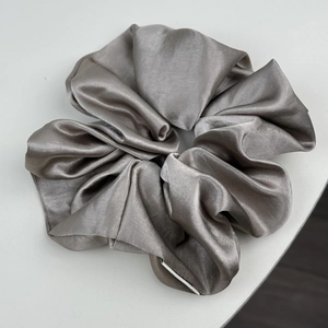 Vue macro détaillée d'un chouchou en satin gris argenté avec des plis doux et brillants