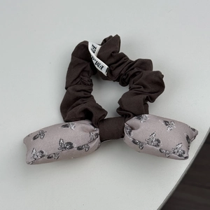 Vue détaillée d'un chouchou à nœud marron et floral rose avec une étiquette tissée
