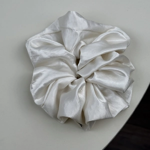 Détail de chouchou en satin blanc avec texture brillante douce et design plissé