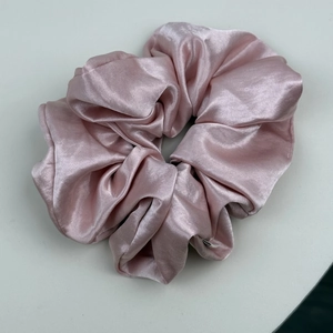 Gros plan sur un chouchou en satin soyeux rose cerisier avec une texture plissée élégante