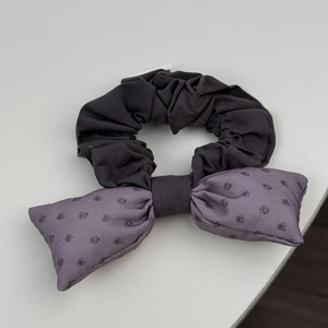 Détail d'un chouchou vintage en tissu noir avec nœud lilas et petits pois mignons
